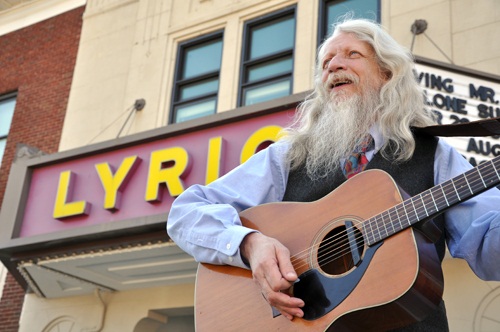 Dr. Moon playing guitar in front of the Lyric Theatre