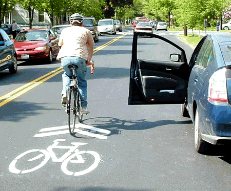 Man biking using sharrows while car door opens