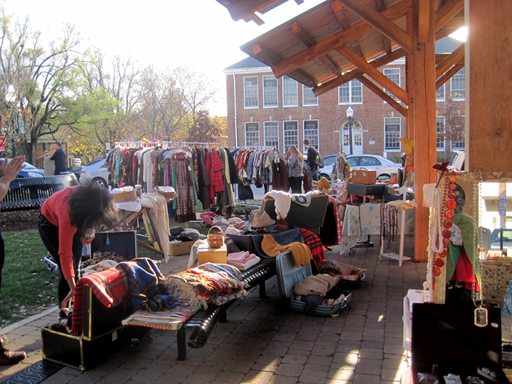 Woman looking at blanket among vintage clothing and items at Vintage Market